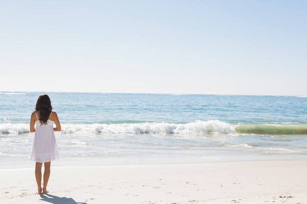 Brunette in white sun dress standing by the water