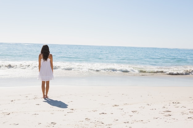 Brunette in white sun dress walking to the sea