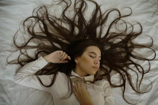 brunette with long hair outstretched on the bed