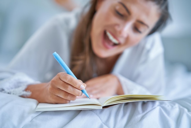 Brunette woman on bad with notepad or book