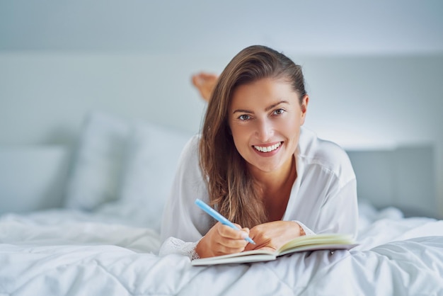 Brunette woman on bad with notepad or book