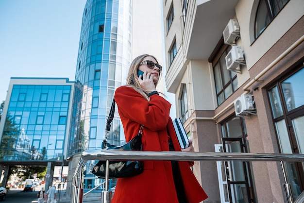 A brunette woman in branded clothes orders a taxi through a smartphone app The concept of a strong woman