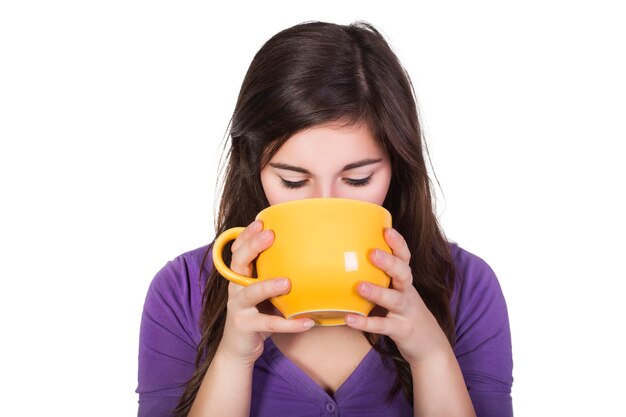 Brunette woman drinking beverage from a big yellow cup isolated on white. copy space