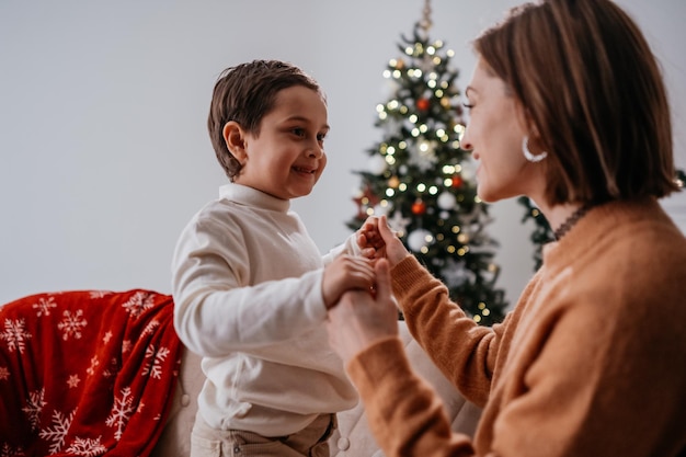 Brunette woman looking at her son with tender smile while celebrating New Year at home