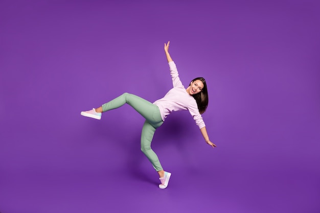 Brunette woman in pastel sweater posing against the purple wall