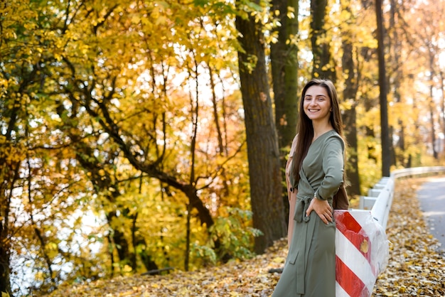 Brunette woman portrait in autumn park wearing olive dress