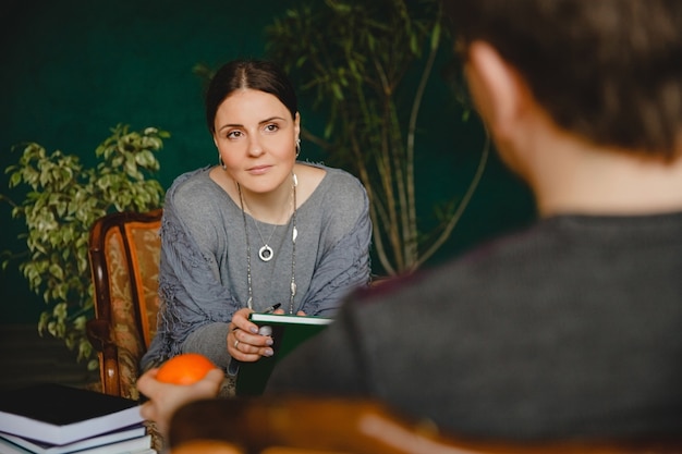 brunette woman psychologist of European appearance conducts a patient's appointment in her office