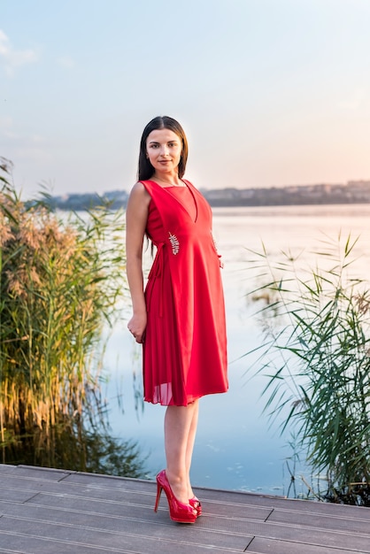 Brunette woman in a red dress on the seashore