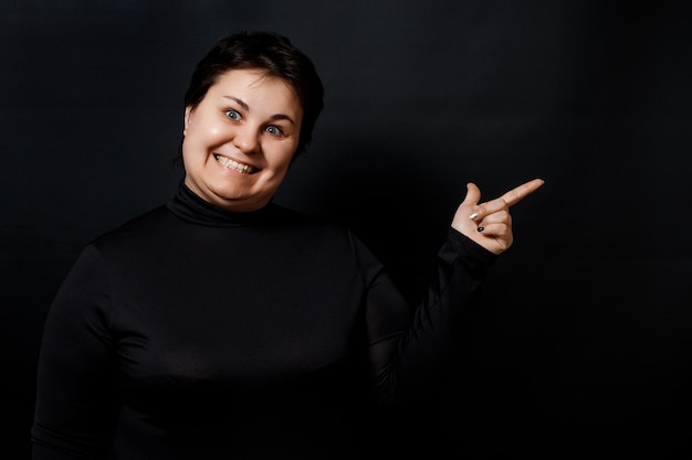 Brunette woman smiling showing finger on black background