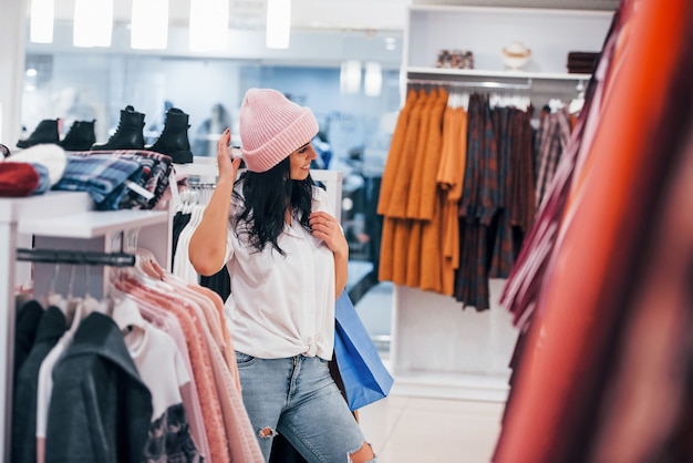 Brunette woman in the supermarket have shopping day and wearing the hat.