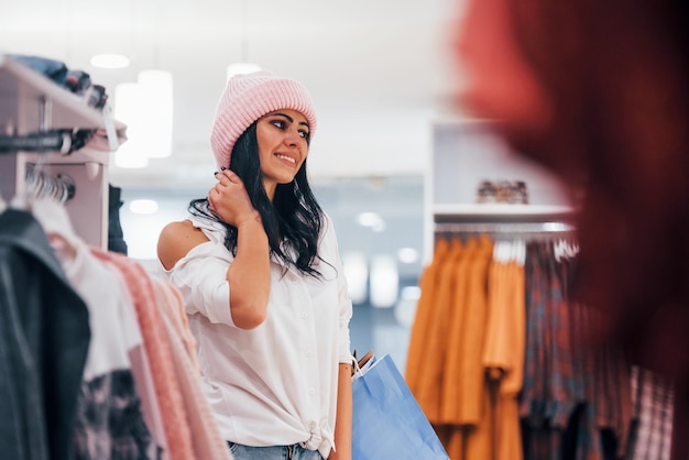 Brunette woman in the supermarket have shopping day and wearing the hat.