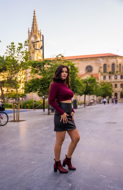 A brunette woman with a leather skirt next to a church lifestyle in the city