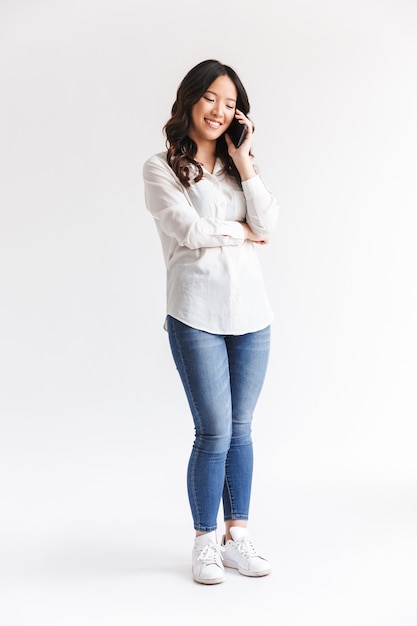 Brunette woman with long dark hair holding and talking on smartphone