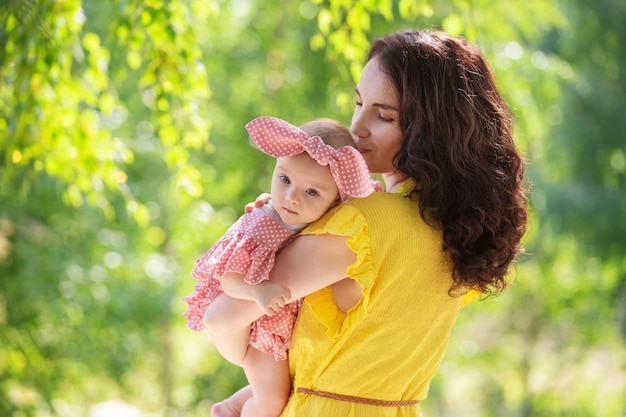 A brunette woman, a young mother with a baby girl walking in the park