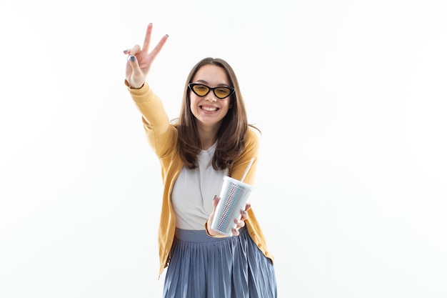 Brunette in a yellow sweater drinks coffee from a brilliant large glass