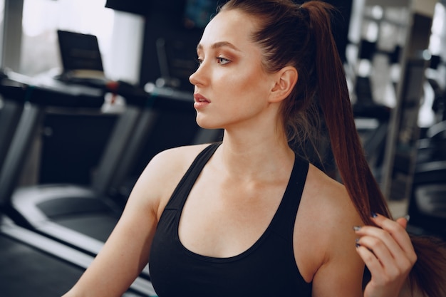 Brunette young woman sitting tired in a gym after workout 