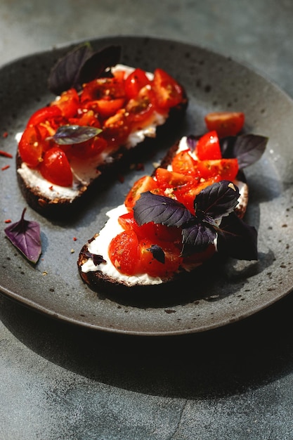 Bruschett with cherry tomatoes cottage cheese basil herbs garlic searved on gray background natural hard light