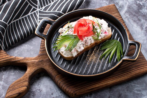 Bruschetta a slice of bread with cheese paste tomato and cucumber Beautifully decorated sandwiches on a plate