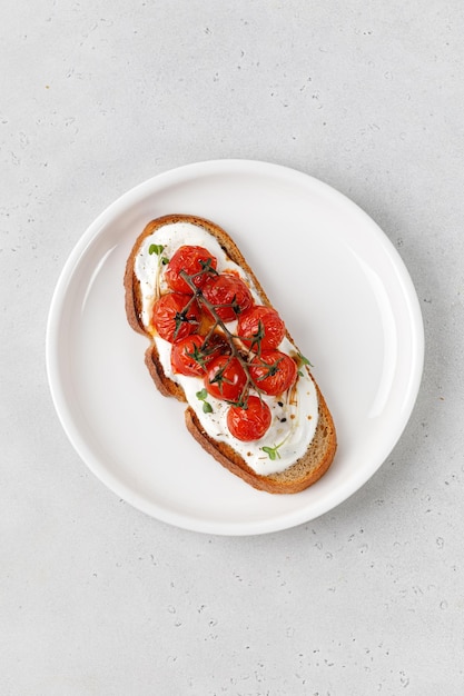 Bruschetta with cream cheese and baked tomatoes cherry on white plate Healthy vegetarian sandwiches