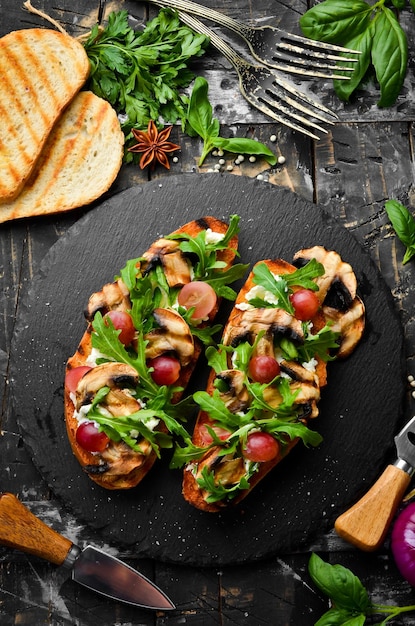 Bruschetta with mushrooms arugula grapes and feta cheese Free space for your text Top view