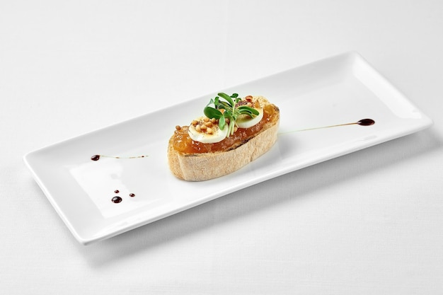 Bruschetta with pear and goat cheese on a white plate against a white background Closeup selective focus