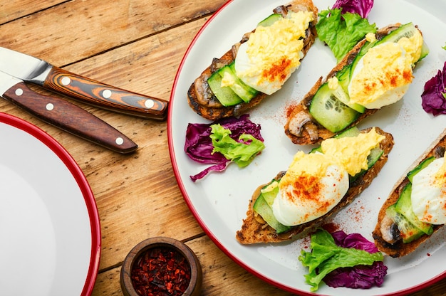 Bruschetta with poached egg,cucumber and stewed mushrooms.Delicious breakfast with eggs benedict