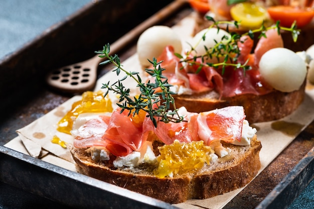 Bruschetta with prosciutto and pesto sauce on plate. Bruschetta with hamon, melon and honey. Spanish appetizer. Italian antipasti. Christmas food.