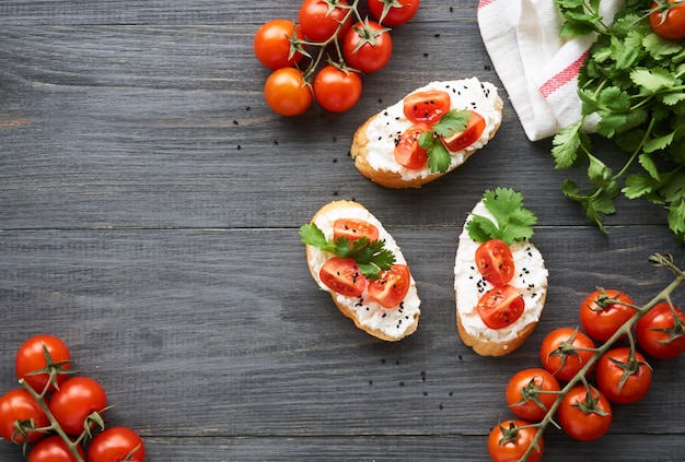 Bruschetta with ricotta cheese, cherry tomatoes and cilantro on wood