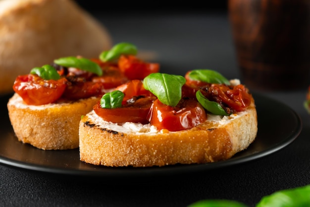 Bruschetta with Ricotto cheese and cherry Tomatoes basil garlic on a black background Closeup