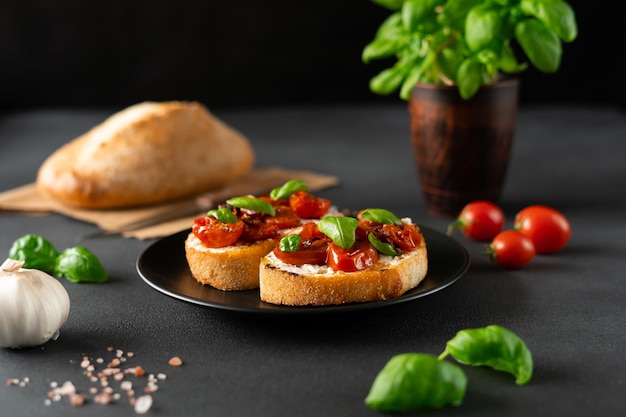 Bruschetta with Ricotto cheese and cherry Tomatoes basil garlic on a black background