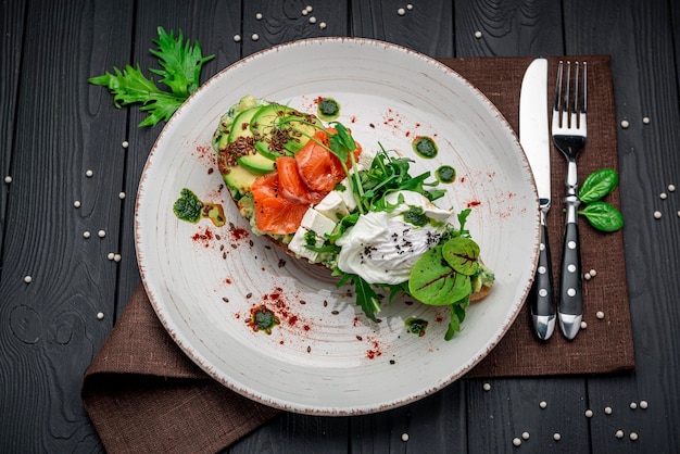 Bruschetta with sliced avocado feta cheese pesto sauce poached egg and salted salmon