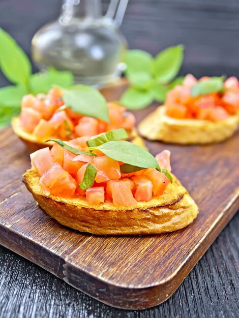 Bruschetta with tomato and basil on dark board