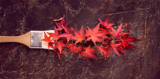 Brush loaded with paint made from red maple leaves Concept image seasonal Autumn home renovation background