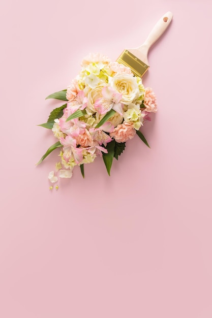 Brush paints with flowers spring concept on pastel pink background Minimal nature flat lay A copy space Vertical view