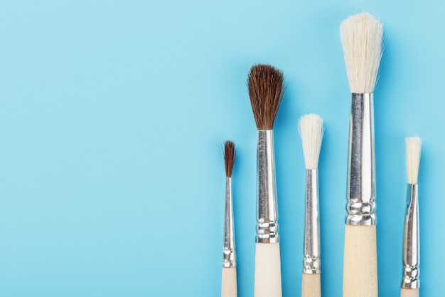 Brushes for drawing made of natural wood and wool. on a blue background.