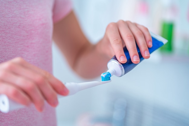 Brushing teeth using ultrasonic electric toothbrush and toothpaste in bathroom at home