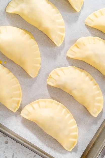 Brushing uncooked breakfast empanadas with eggs and sweet potato with egg wash