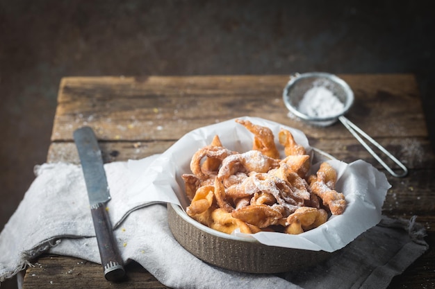 Brushwood - russian traditional cookies with powdered sugar. Plate with hvorost on wooden table