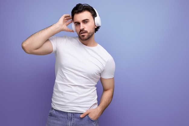 Brutal brunette man in a white tshirt listens to music on headphones