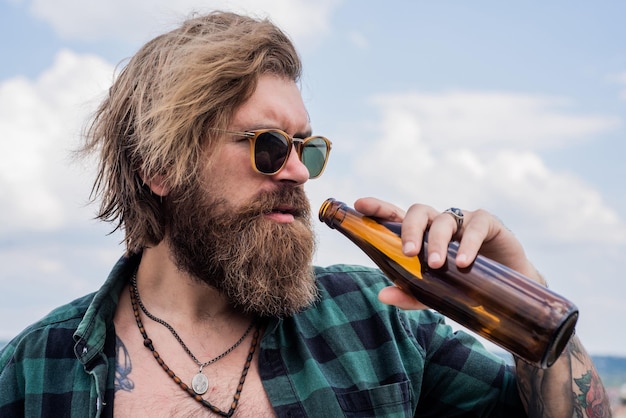 brutal caucasian hipster with glass water bottle. male bachelor lifestyle. bearded man drink beer. handsome brutal man. time to relax. mature hipster with beard drinking beer.