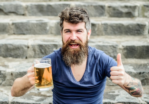 Brutal male needs refreshment Bearded man with beer glass outdoor weekend relax drink alcoholic beer beverage Mature hipster with beard hair drinking beer Enjoying carefree time