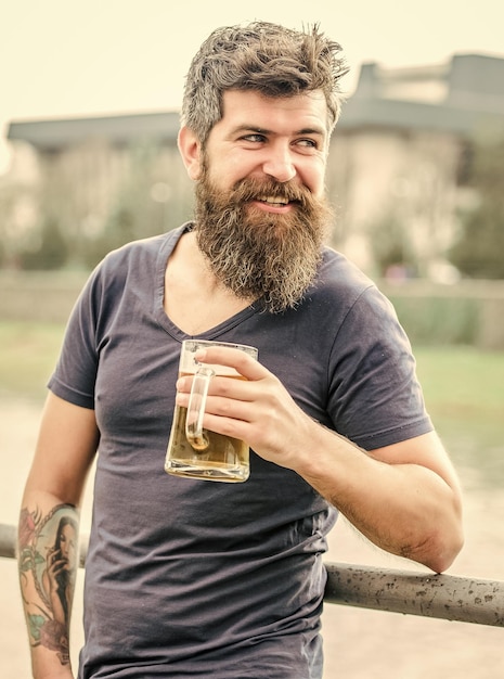 Brutal male needs refreshment weekend relax drink alcoholic beer beverage Mature hipster with beard hair drinking beer Bearded man with beer glass outdoor Friends and beer