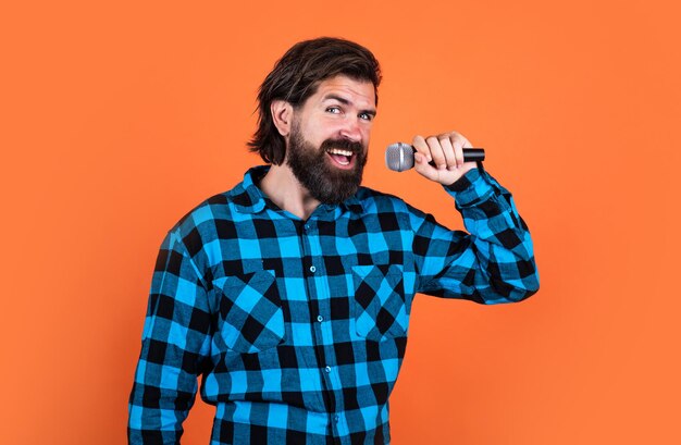 Brutal man in checkered shirt has long beard sing in microphone music