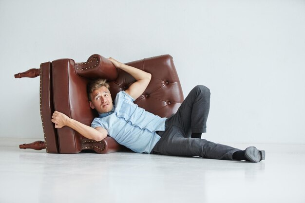 Brutal man in a shirt with short sleeves sitting in the chair his fists clenched slightly bent under