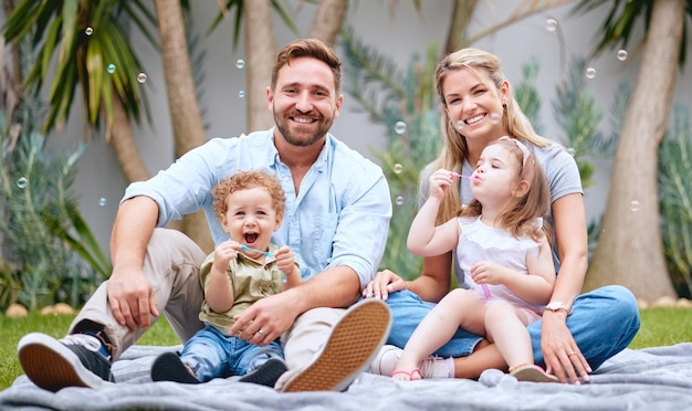 Bubbles garden and portrait of parents with children having fun on weekend holiday and relaxing Family love and mom and dad with kids sitting on grass in backyard doing cute outdoor activity