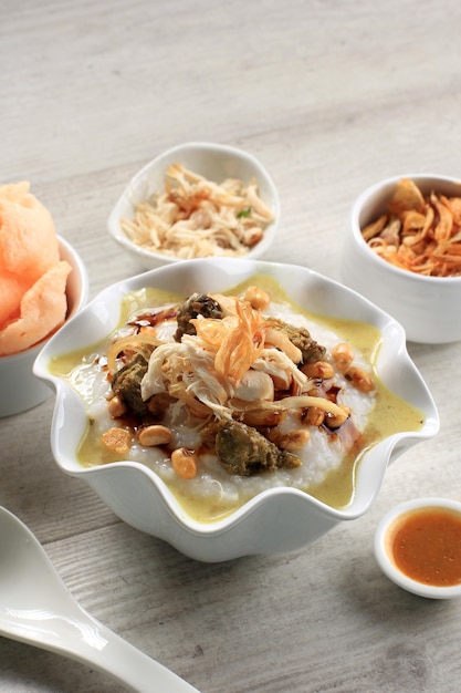 Bubur Ayam or Indonesian Rice  Porridgew with Shredded Chicken. Served with Kerukpuk (Cracker), Soy Sauce, Fried Soy Bean, and Sambal