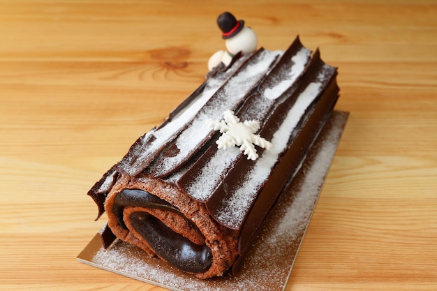 Buche de Noel or Chocolate Yule Log Cake for Christmas Sprinkle with Icing Sugar on Wooden Table