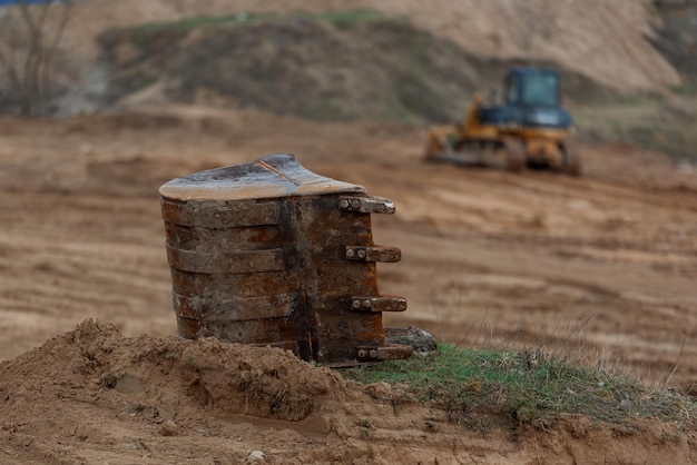 The bucket of the excavator lies in the foreground the bulldozer in the background