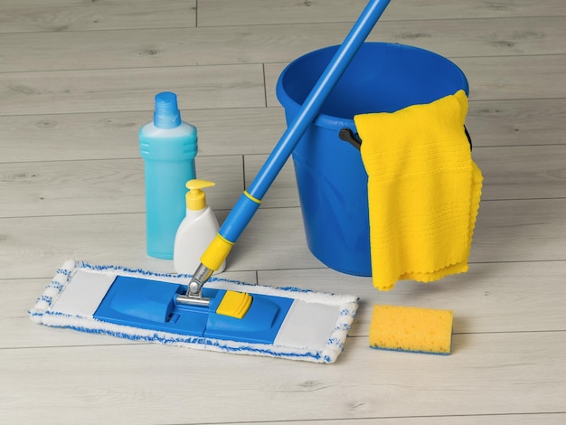 Bucket mop rag and detergents on the wooden floor Home and office cleaning kit The concept of maintaining cleanliness Flat lay