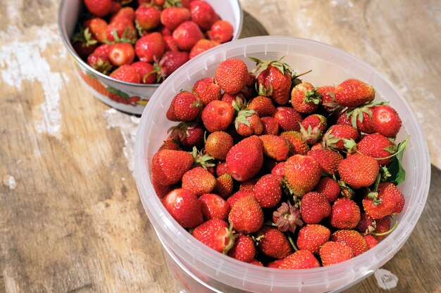 A bucket of strawberries on a wooden floor top view victoria harvest in a bucket